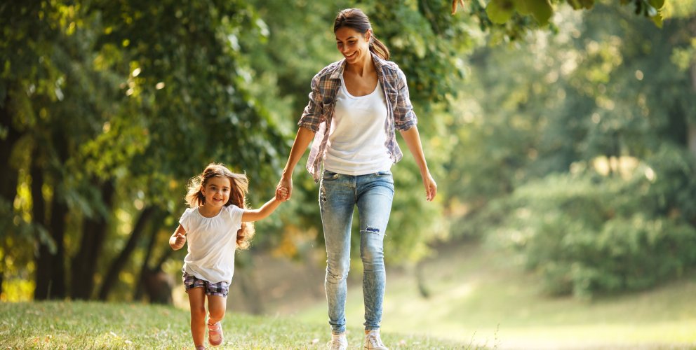 Jeune femme et fillette, souriantes, se promenant dans un parc par une belle journée ensoleillée